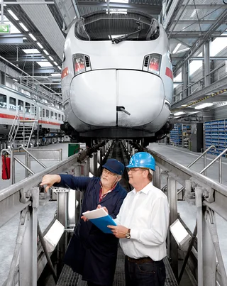 Two employees check elevated tracks in front of a train.